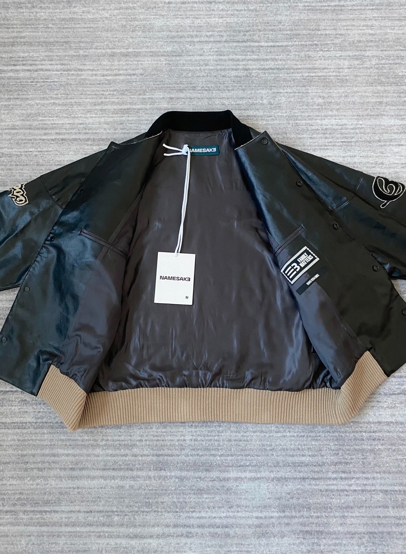 beige baseball jacket with leather sleeves